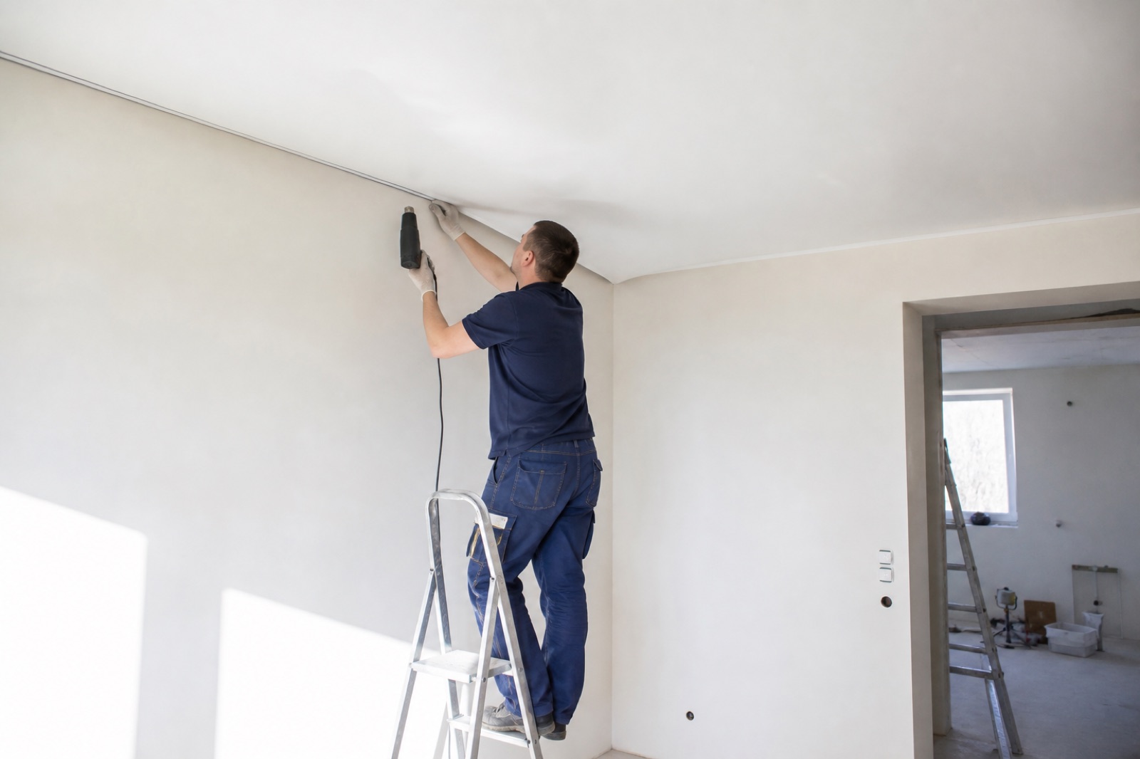 Poseur Drakot tendant une toile de plafond au pistolet à chaleur